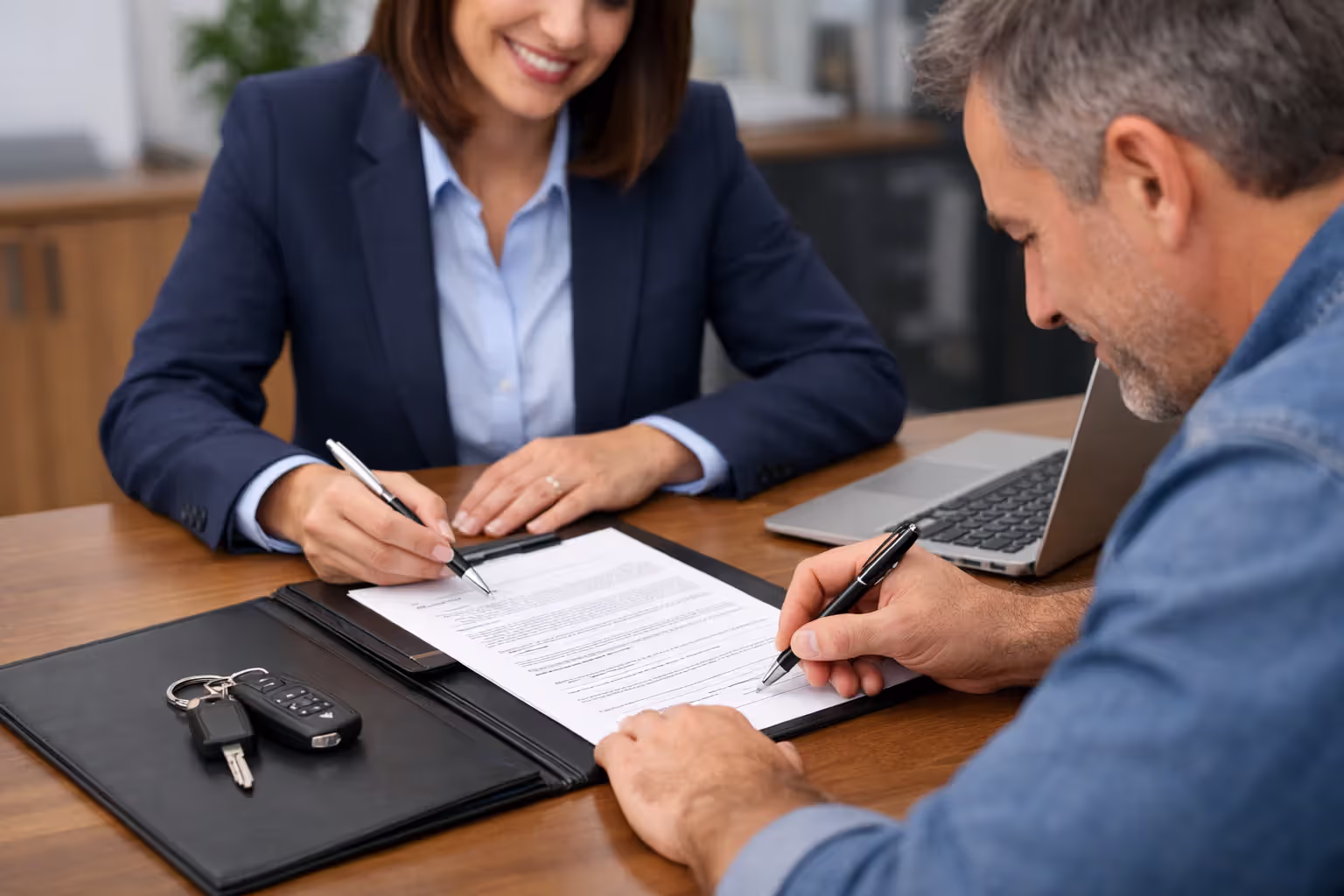 Borrower signing secured loan documents with car keys on the table
