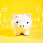 A white piggy bank with drawn muscular arms.