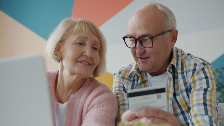 Elderly couple looking at laptop with credit card
