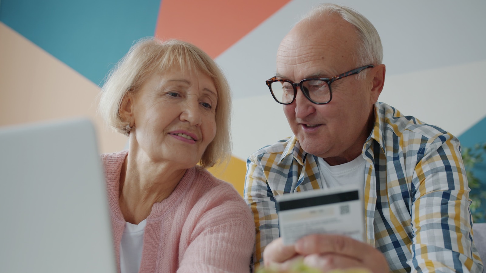 Elderly couple looking at laptop with credit card